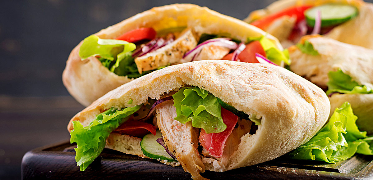 Pita stuffed with chicken, tomato and lettuce on wooden background. Banner. Middle Eastern cuisine.